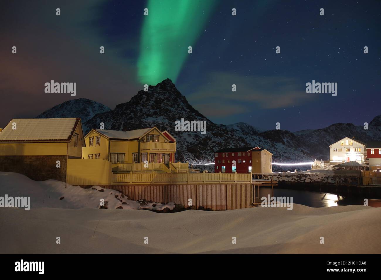 Snowy landscape with houses, northern lights, aurora borealis ...