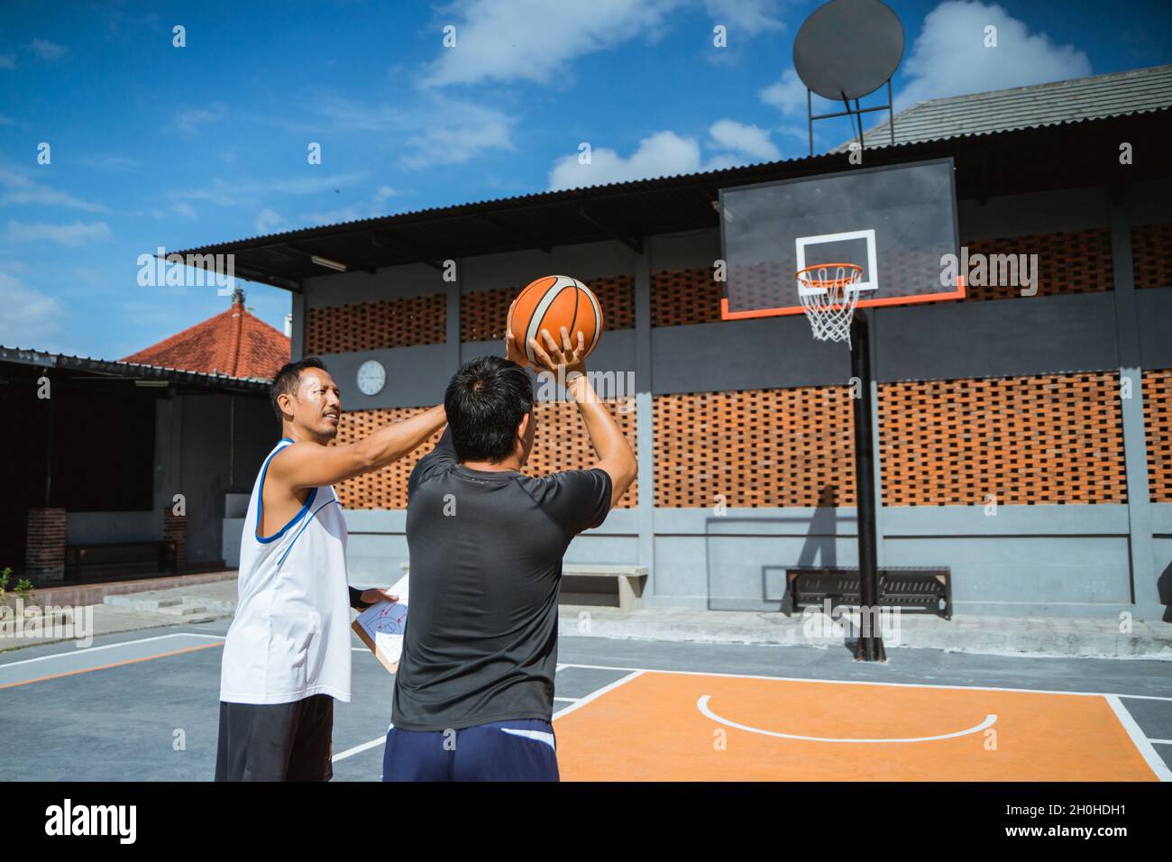 a coach teaches a basketball player shooting techniques during