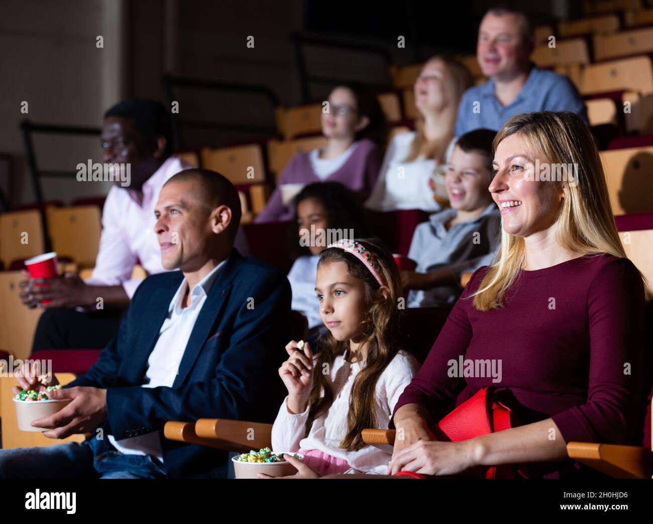 Cheerful family watching a movie and eating popcorn in cinema Stock ...