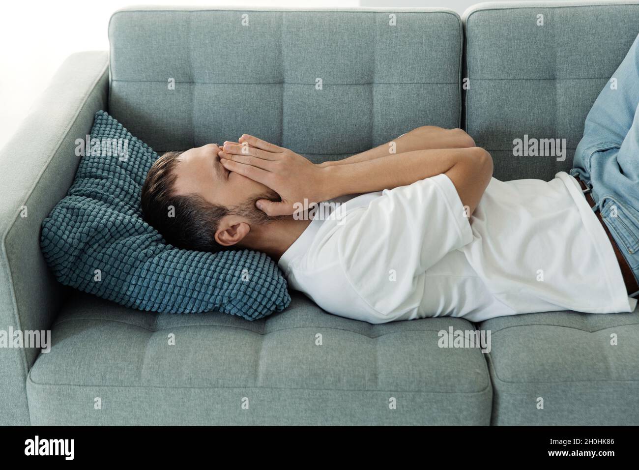 Depressed man lying on couch cry hide face suffer from pain, anxiety, stress or nervous breakdown Stock Photo