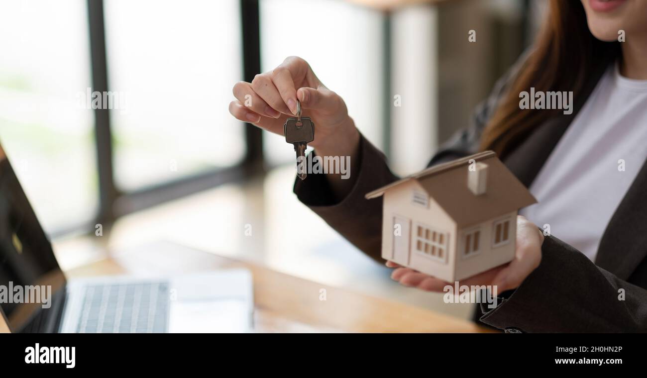 Real estate agent hand holding house model and keys Stock Photo - Alamy
