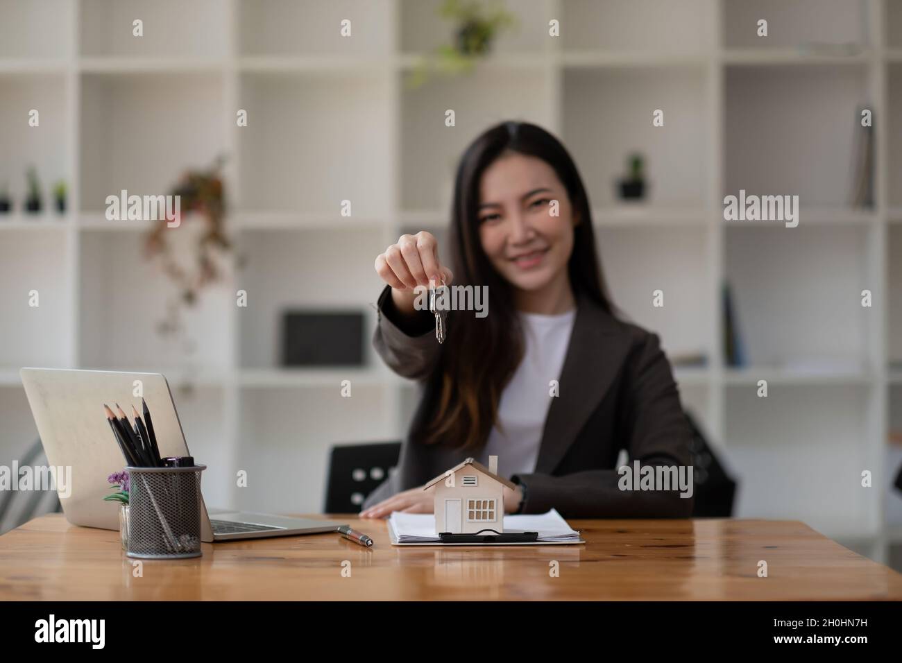 Real estate agent hand holding house model and keys Stock Photo - Alamy