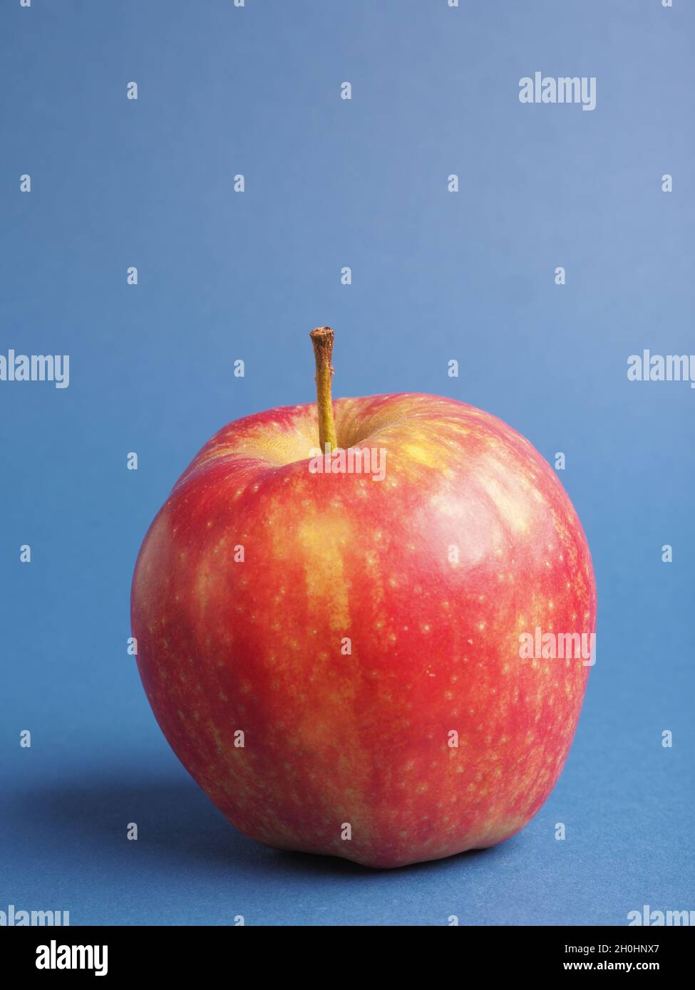 One fresh red organic apple on a blue studio background, horizontal  landscape view Stock Photo - Alamy