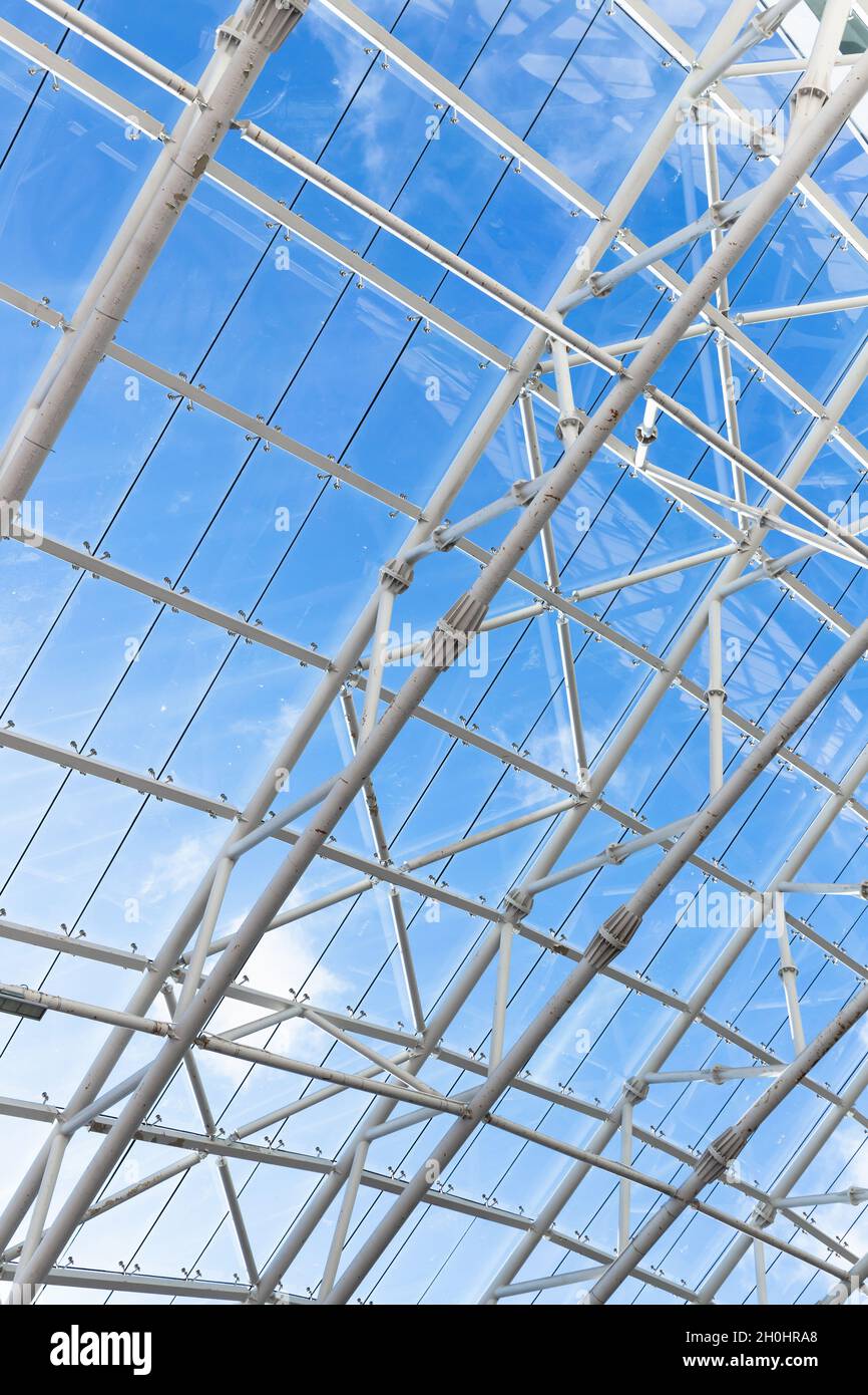 Abstract contemporary architectural vertical photo. Internal structure of roof with metal frame and glass under blue sky on a daytime Stock Photo