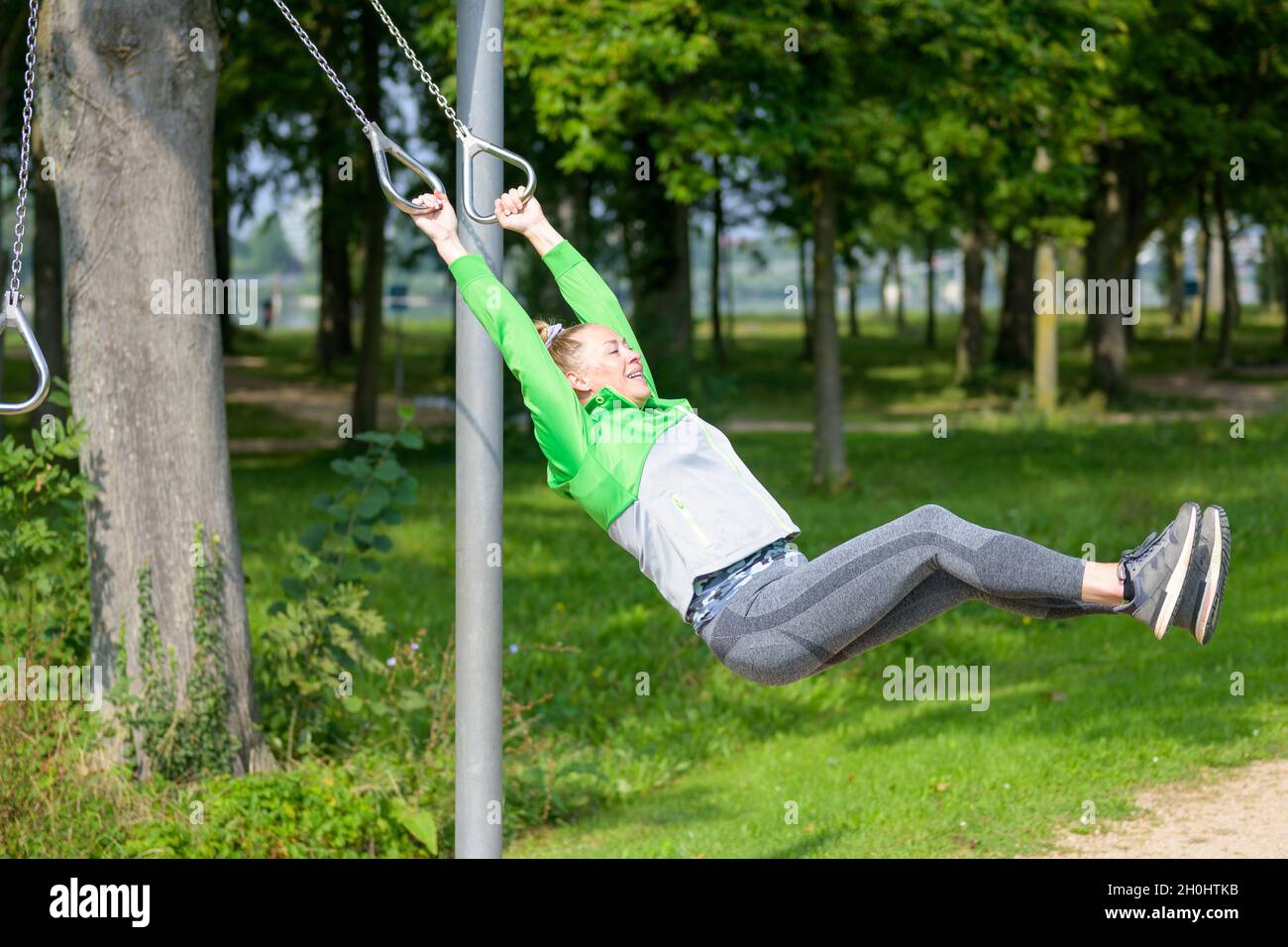 Fit healthy sporty lady exercising on rings at an outdoors sporting