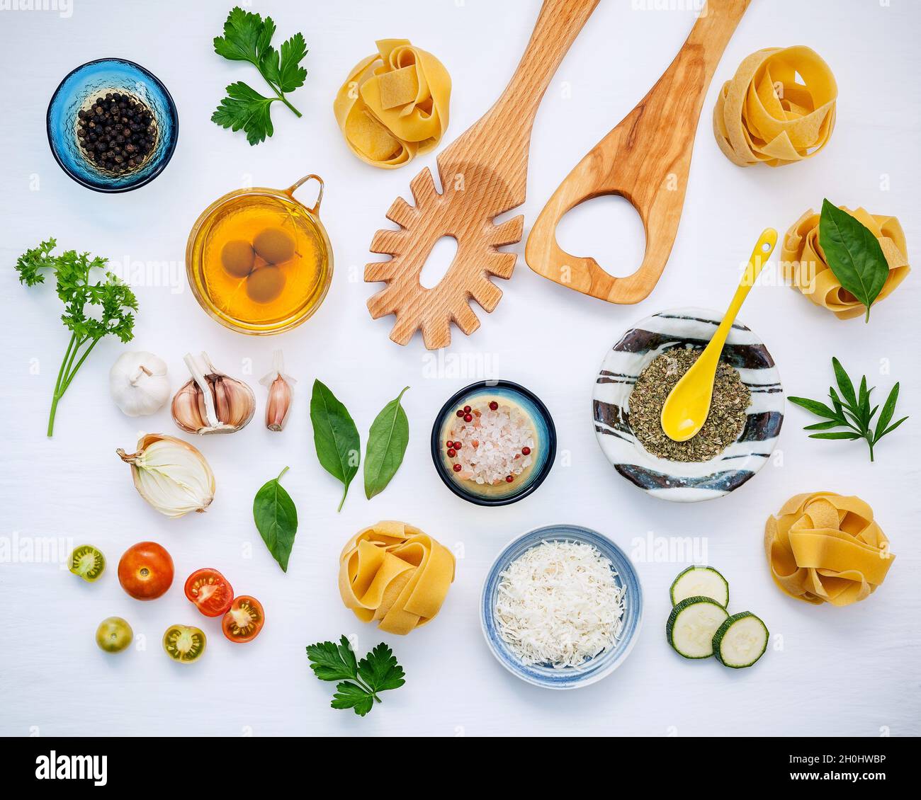 Italian foods concept and menu design. Dried homemade Fettuccine with wooden spatula and  ingredients sweet basil ,tomato ,garlic ,parsley ,bay leaves Stock Photo