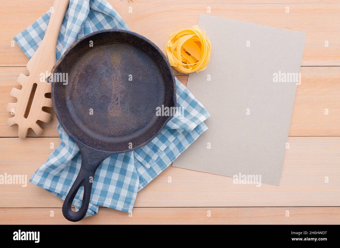 Food background for tasty Italian dishes with empty cast iron skillet and  pasta ladle on wooden background. Top view italian foods concept and menu d Stock Photo