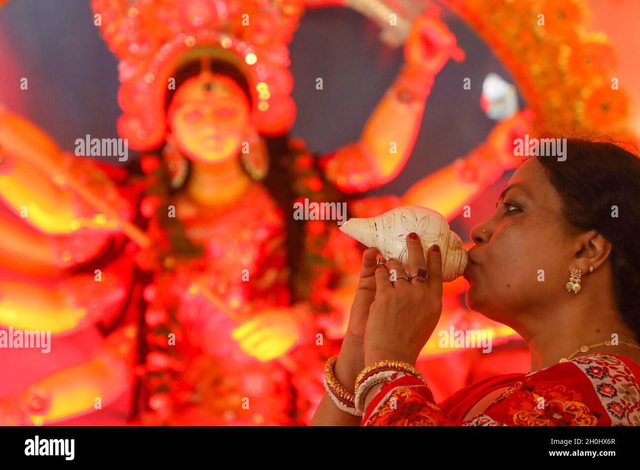 Dhaka, Bangladesh. 12th Oct, 2021. A Hindu Devotee seen blowing conch shells to Goddess Durga, during the festival.7th day of Durga puja festival known as Saptami, the biggest Hindu festival running for 9 days all over Bangladesh. Credit: SOPA Images Limited/Alamy Live News Stock Photo