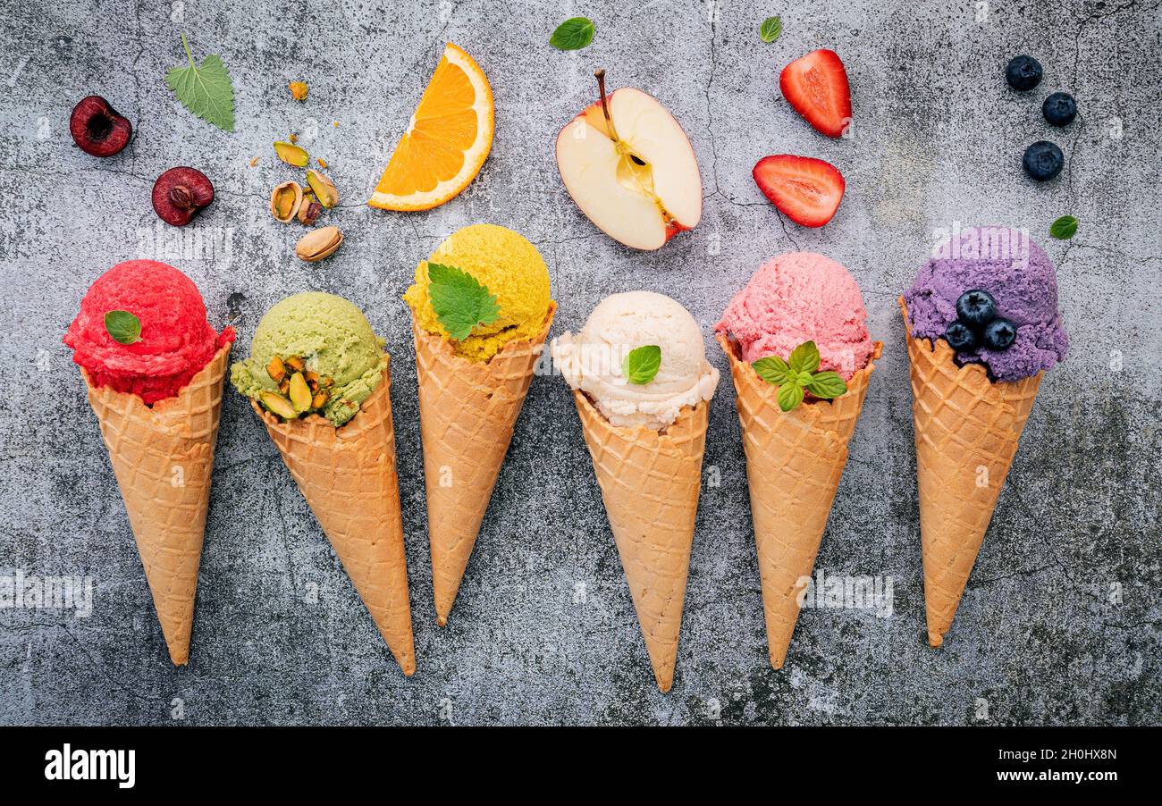 Various of ice cream flavor in cones blueberry ,green tea ,pistachio ,almond ,orange and cherry setup on dark stone background . Summer and Sweet menu Stock Photo