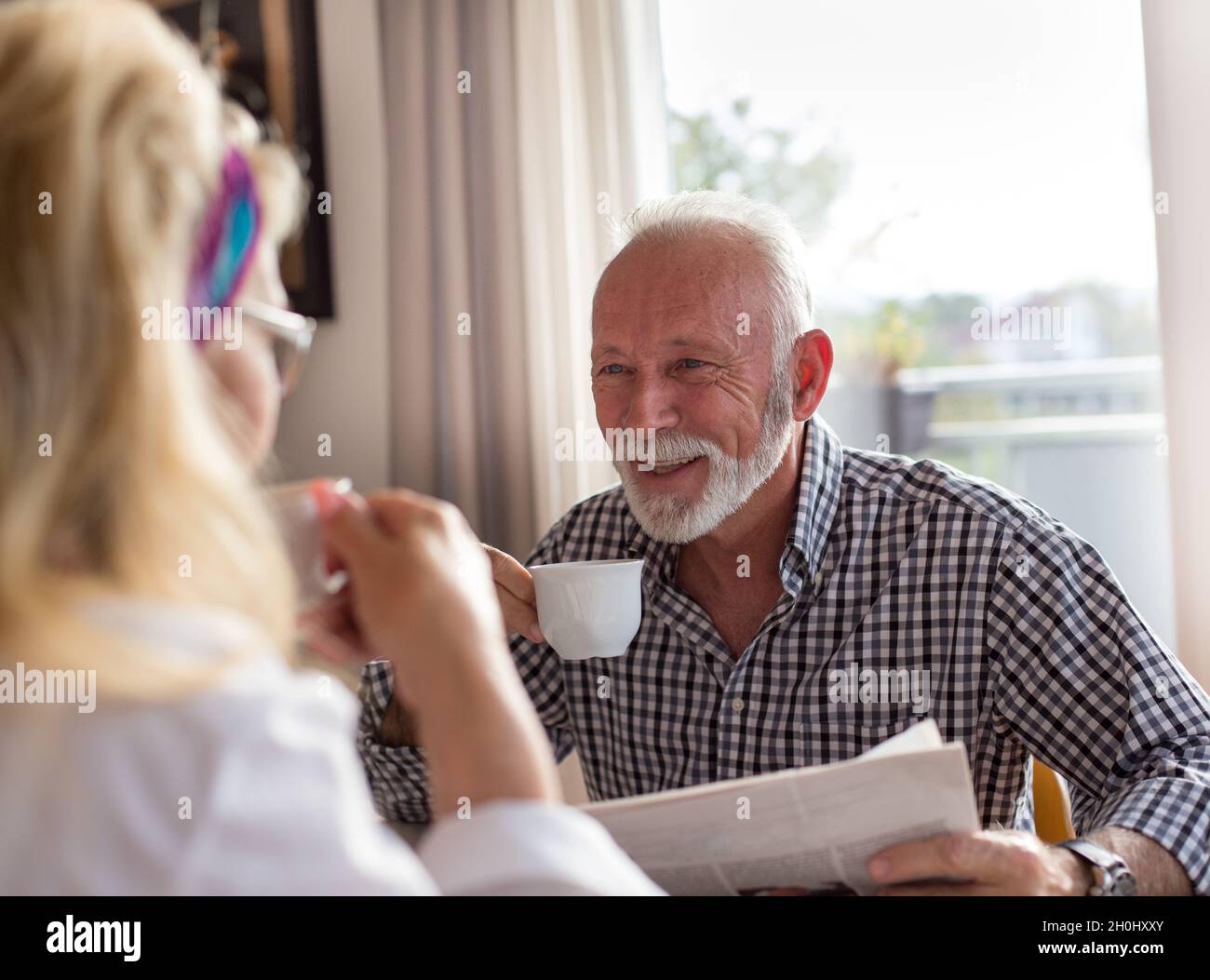 Elderly couple sitting at dining table in the morning drinking coffee ...