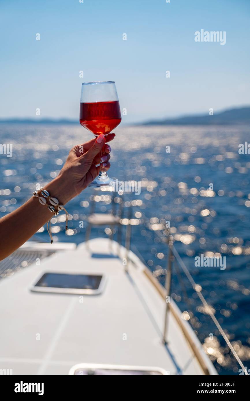 Female hand holding glass of wine on sea background Stock Photo - Alamy