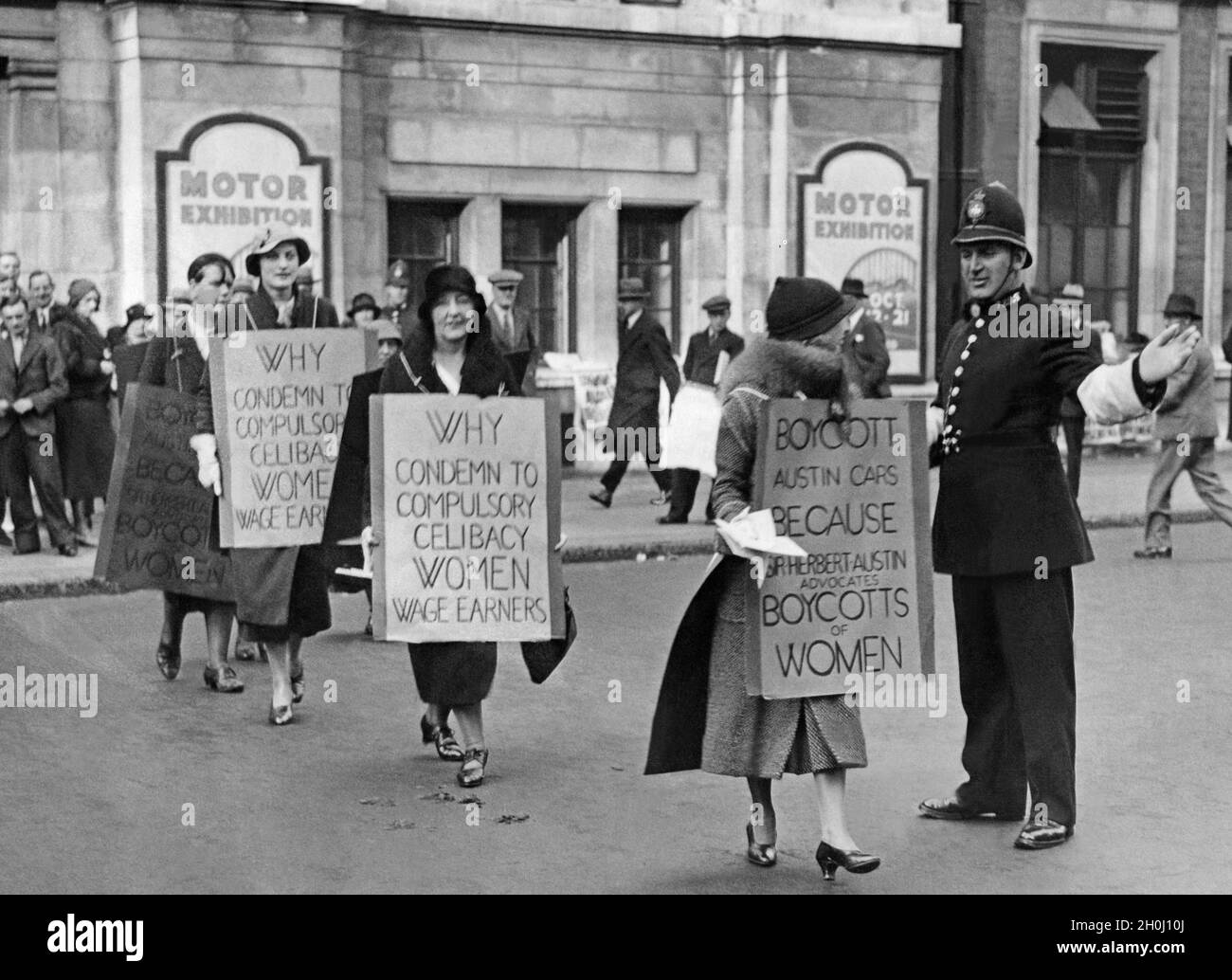 'A policeman regulates the traffic in front of the entrance to the ''Motor Exhibition'' at the Olympia in London and allows the demonstrators to cross the street. The women demonstrate with placards for fairer wages and working conditions and call for a boycott of Sir Herbert Austin. [automated translation]' Stock Photo