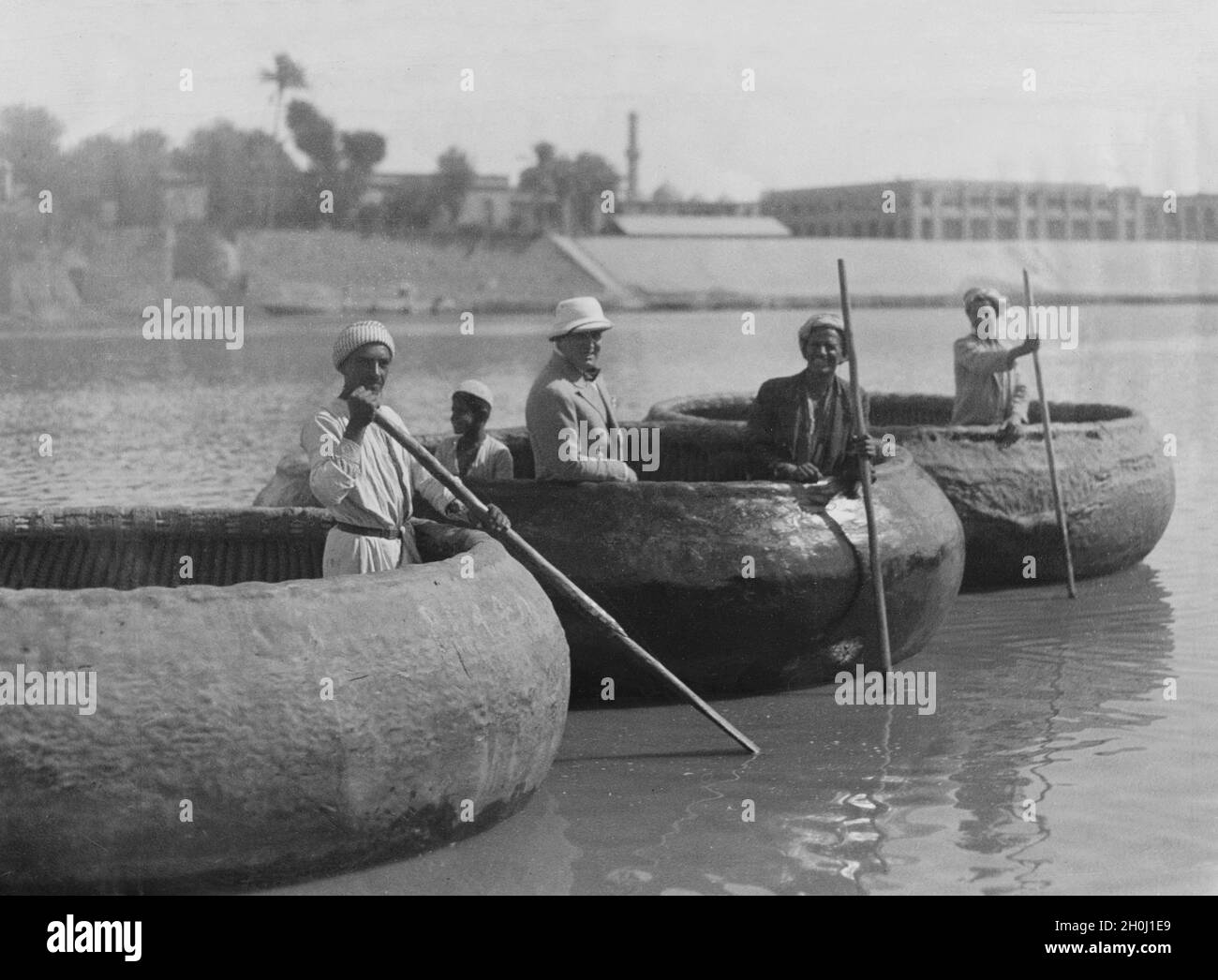 A European traveller with Iraqis in boats, as they are used by the population on the Euphrates and Tigris. They are woven from reeds, palm leaf strips and twigs and then covered with asphalt / tar to make them watertight. [automated translation] Stock Photo