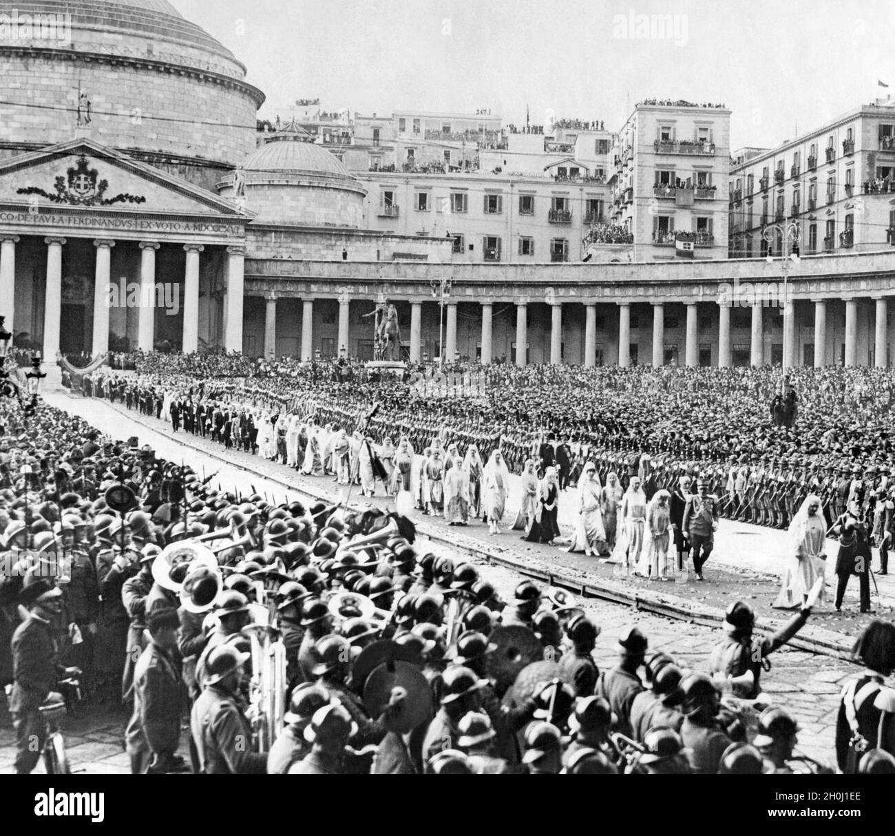 On 5 November 1927, the wedding of Amadeus of Savoy, Duke of Aosta, to Anna d'Orléans took place in the church of San Francesco di Paola (in the background) in Naples. In the picture, the wedding party is just leaving the church after the ceremony and striding across the Piazza del Plebiscito to the royal palace. In the square, thousands of curious people cheer the newlyweds. Grand Admiral Paolo Thaon di Revel walks ahead with his wife Irene (right). [automated translation] Stock Photo