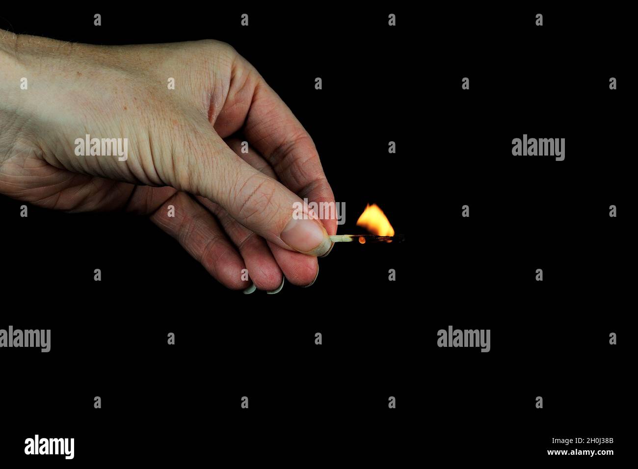 Hand holding burning match stick on black background Stock Photo