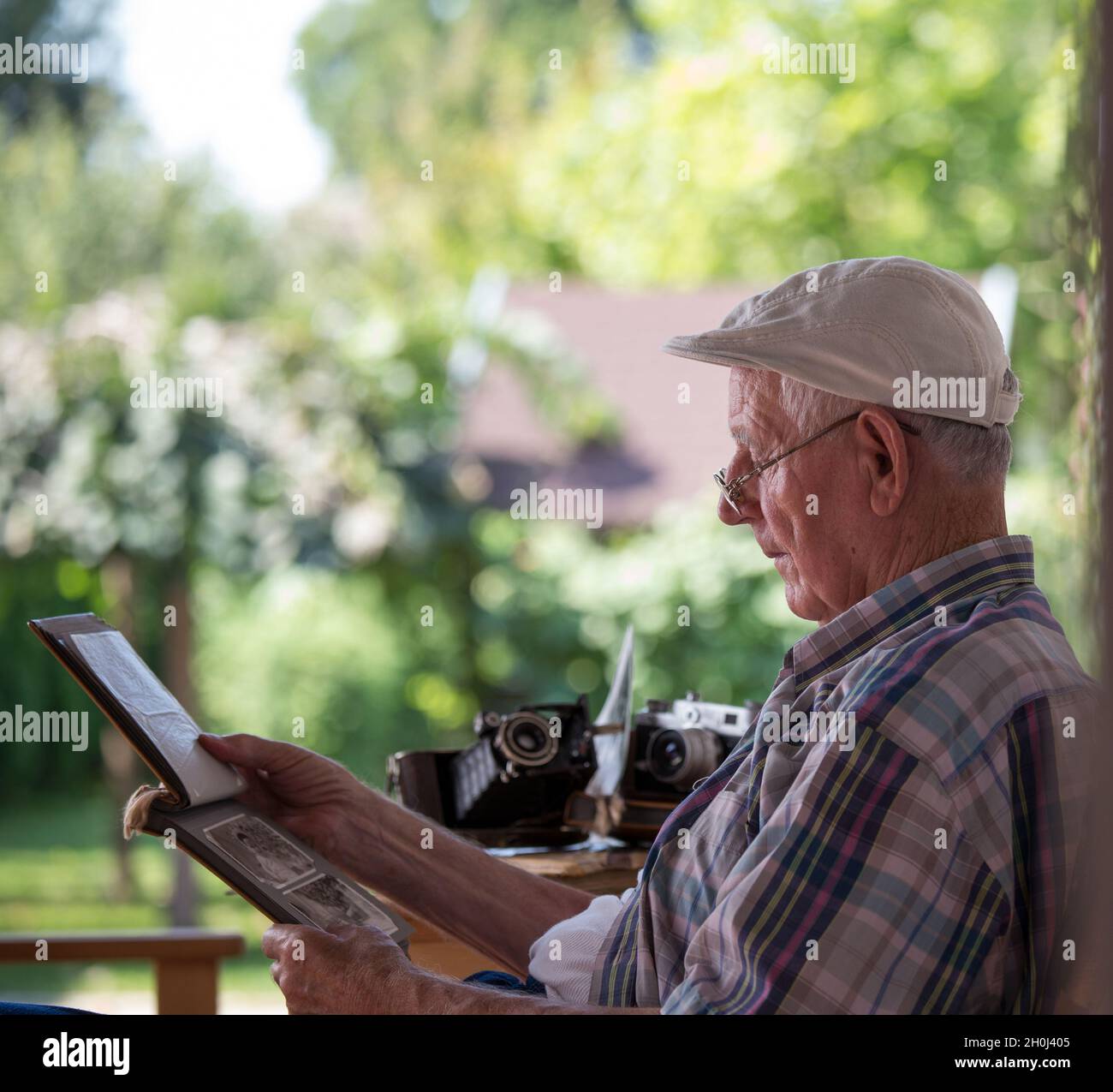 Senior man sitting in garden and looking at old photos. Nostalgia and ...