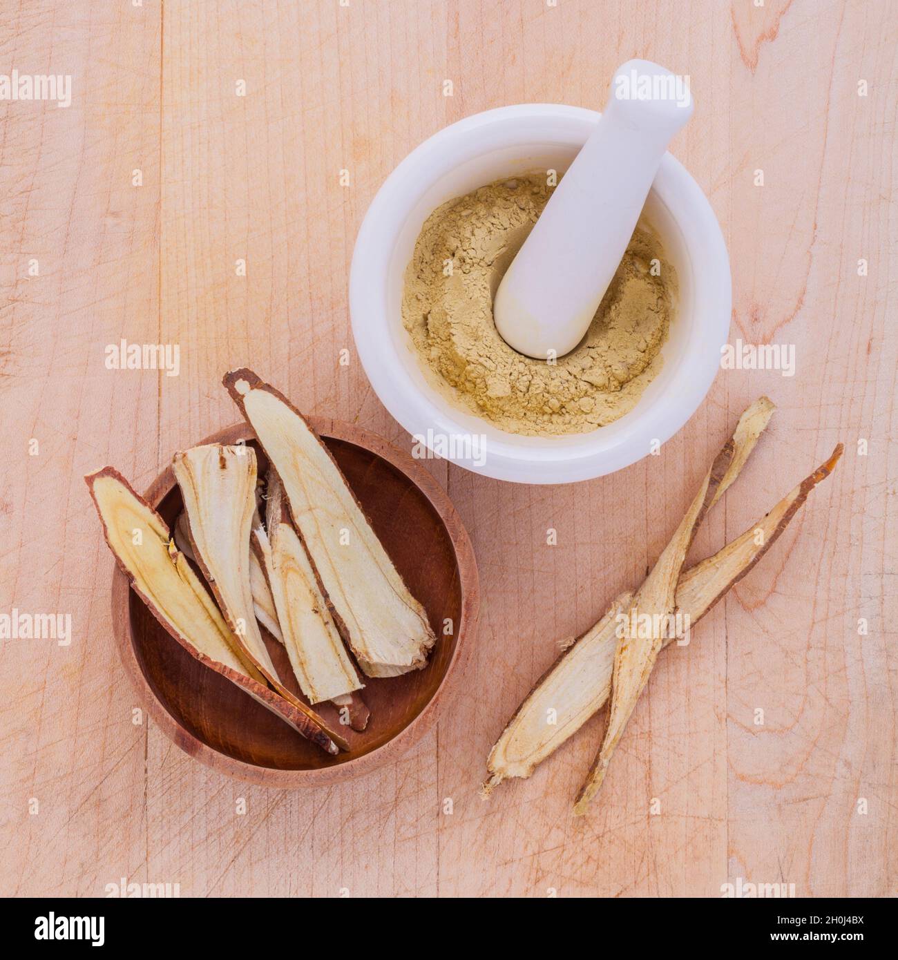 Licorice herbal medicine including powder, chopped and sliced root and mortar on wooden table