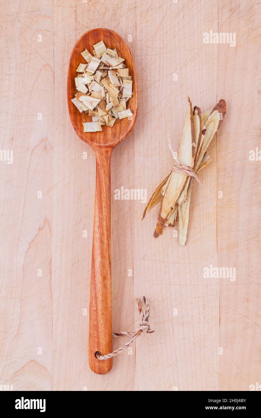Licorice herbal medicine in wooden spoon, chopped and sliced on wooden table Stock Photo