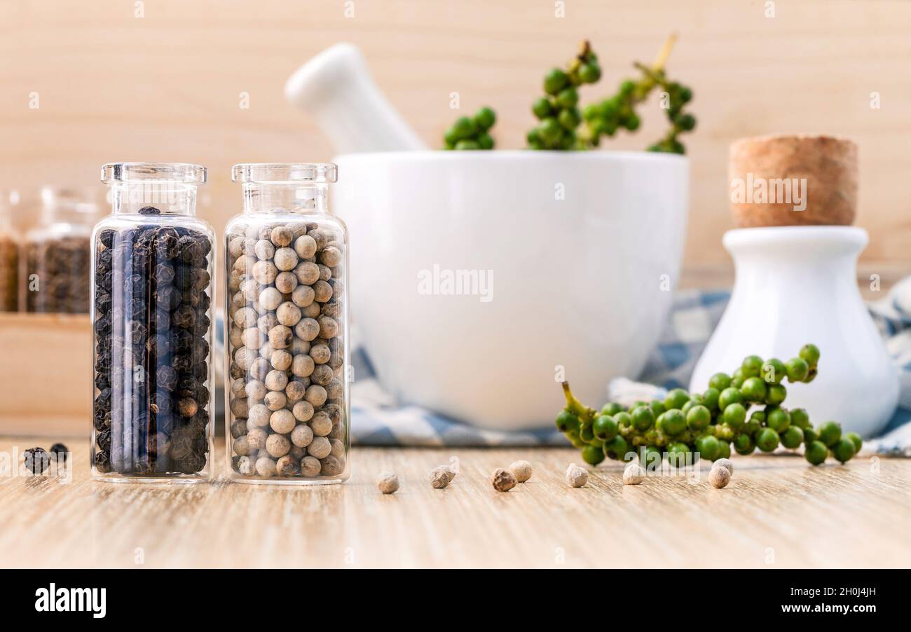 https://c8.alamy.com/comp/2H0J4JH/assorted-of-spice-bottles-condiment-black-pepper-white-pepper-and-green-pepper-seeds-with-mortar-on-wooden-background-2H0J4JH.jpg