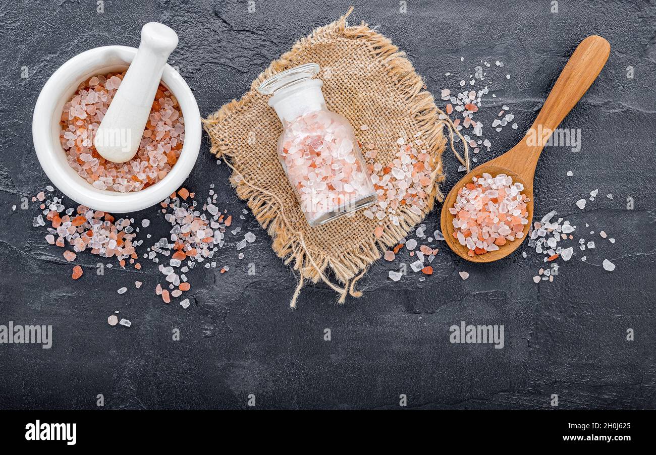 Himalayan pink salt on dark concrete background. Himalayan salt commonly used in cooking and for bath products such as bath salts. Stock Photo