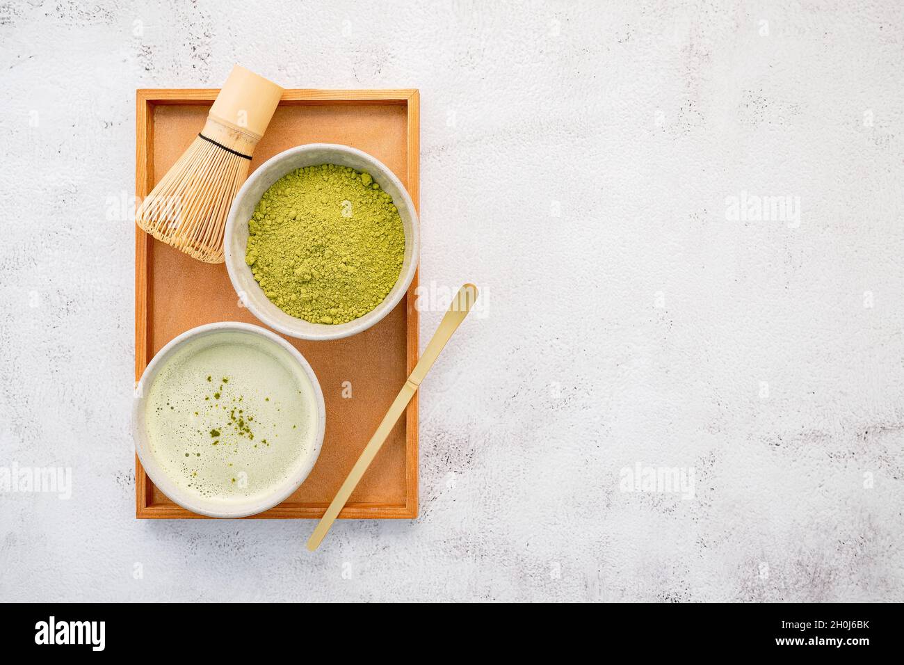 Matcha green tea powder with bamboo matcha whisk brush setup on white