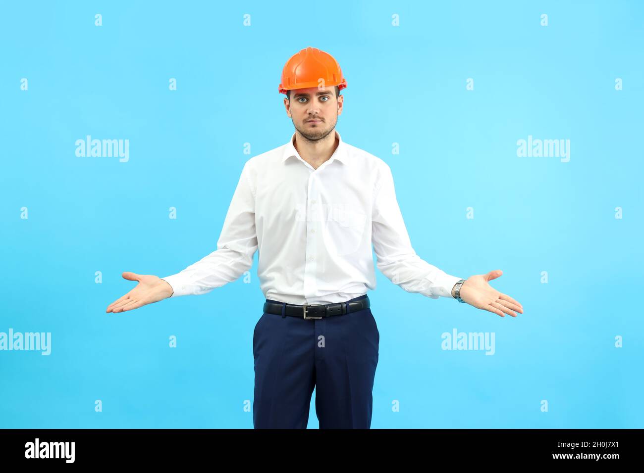 Businessman builder in misunderstanding on blue background. Stock Photo