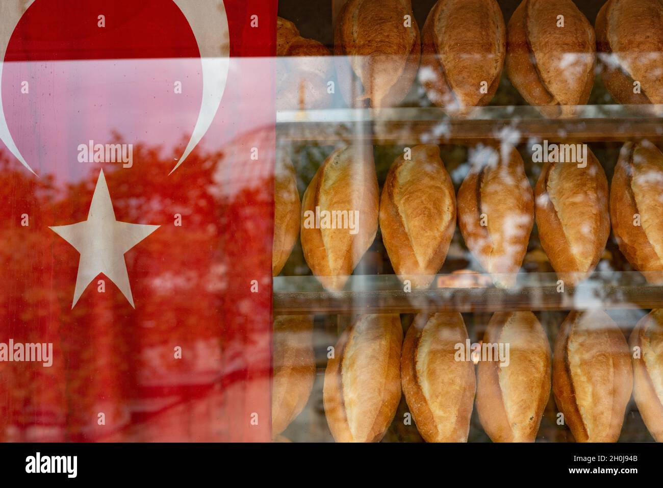 Istanbul, Turkey. October 12th 2021 Traditional Turkish bread loafs for sale inside a typical bakery window beside a Turkish flag Stock Photo