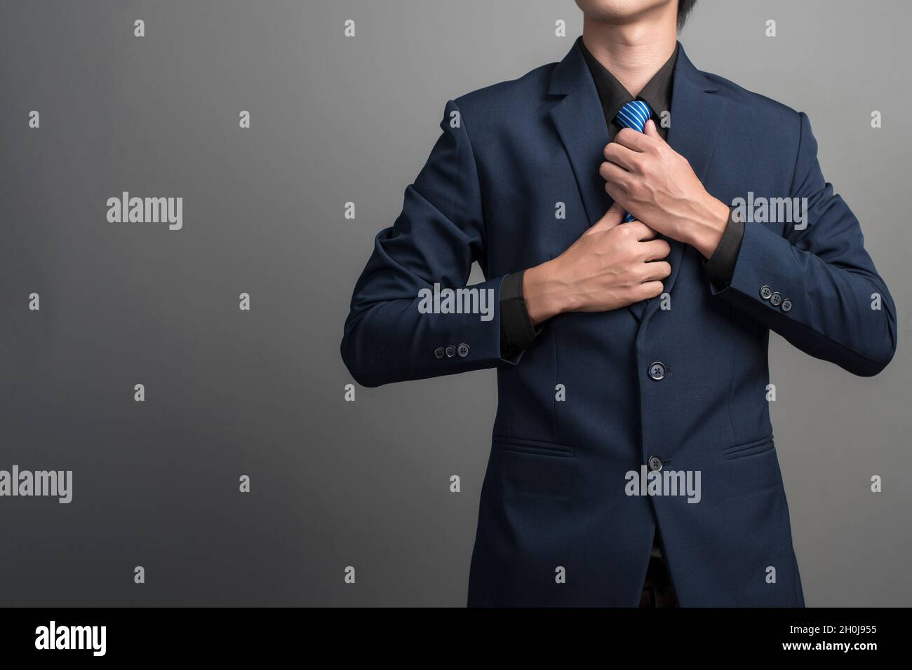 Close up of businessman in blue suit Wearing a necktie on gray background Stock Photo