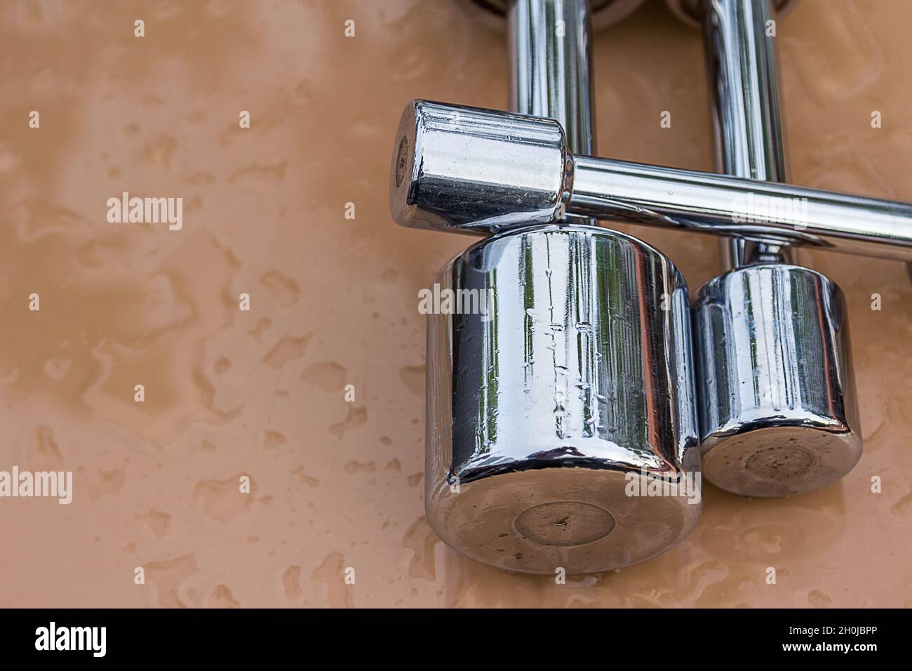 Glossy Steel Dumb bells set on brown table with water drop background Stock Photo