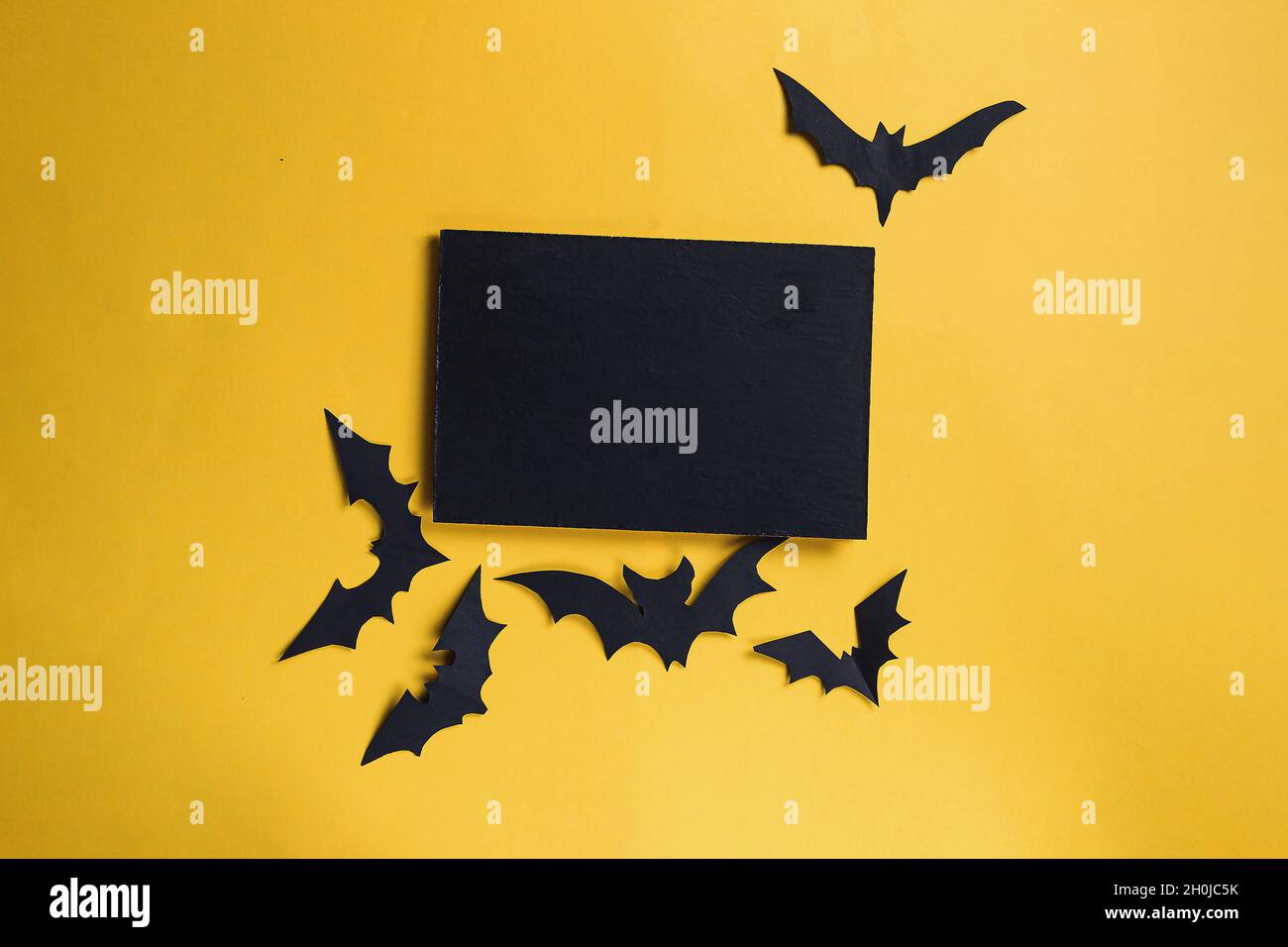 Yellow background with bat cutouts and a black note with copy space for ...