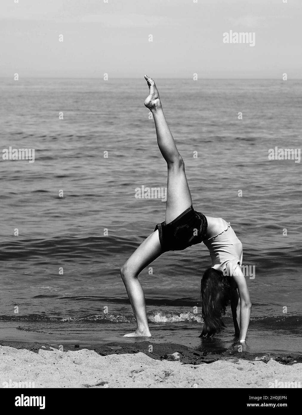 athletic skinny girl with long slender legs during a gymnastic exercise by the sea in summer with black and white effect Stock Photo Alamy