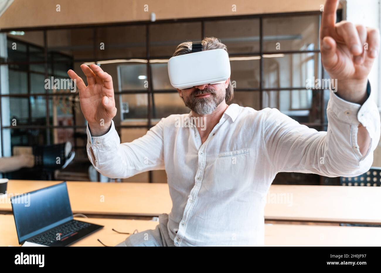 senior business man sitting in his office and using mixed reality to develop a new project Stock Photo