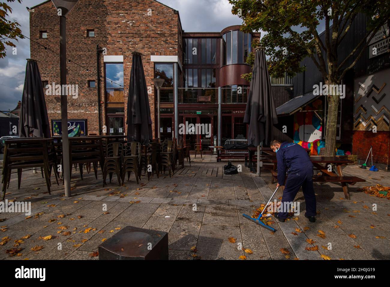 A man sweeps up outside a closed bar in the Ropewalks district of Liverpool as the region heads into a level 3 local lockdown, in Liverpool, U.K Stock Photo
