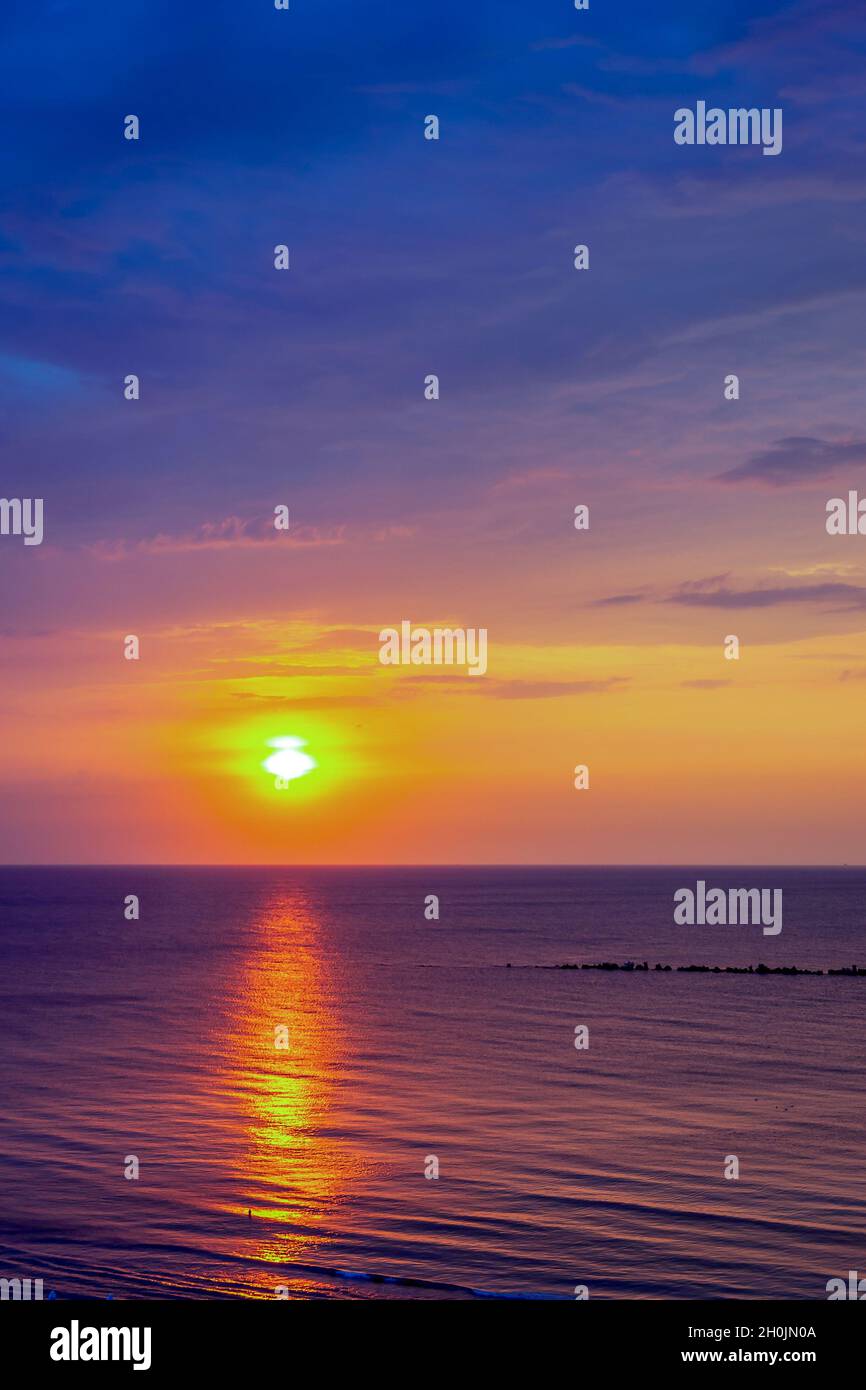Breathtaking scenery of a golden sunset at the ocean with purple and ...