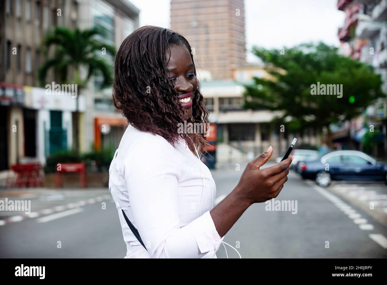 beautiful african young woman walking down the street using a mobile ...