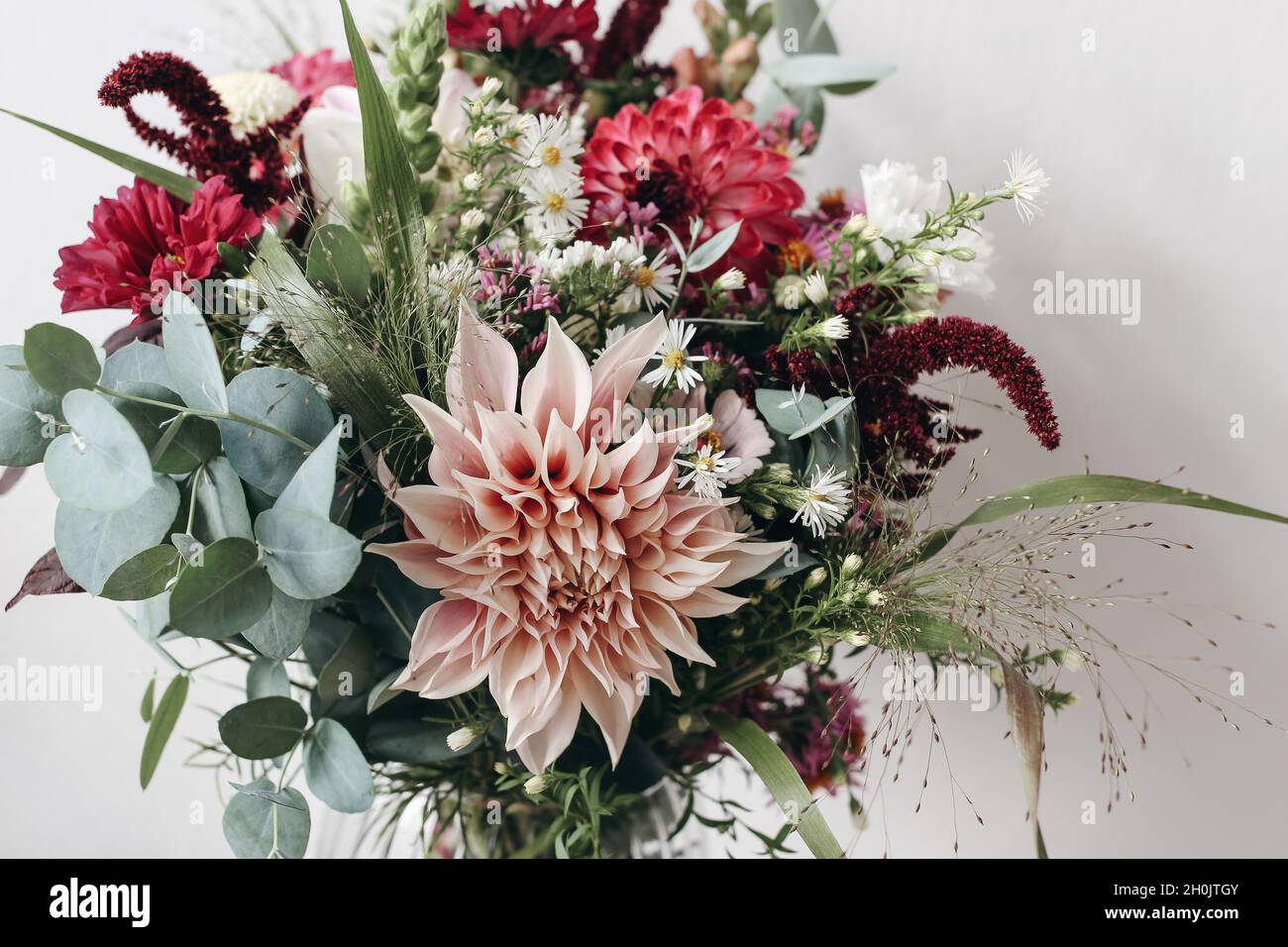 Closeup of colorful flowers. Moody autumn wedding or birthday bouquet. Pink and burgundy dahlia, cosmos and aster flowers. Amaranthus and eucalyptus Stock Photo