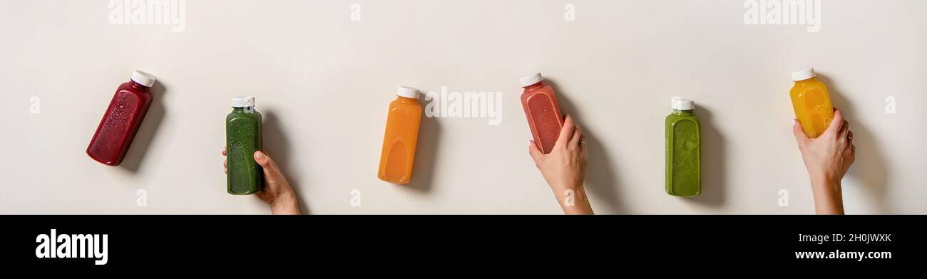 Human hands holding fresh juices in bottles, wide composition Stock Photo