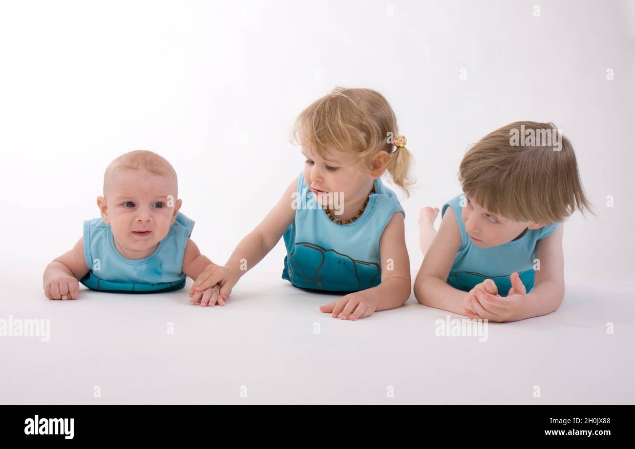 three little children lying next to each other in prone position Stock Photo