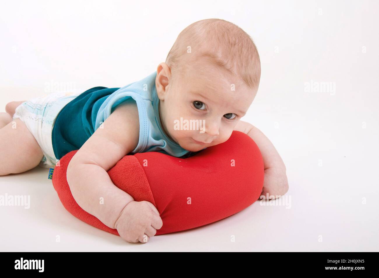 baby lying in pampers on a red neck pillow Stock Photo