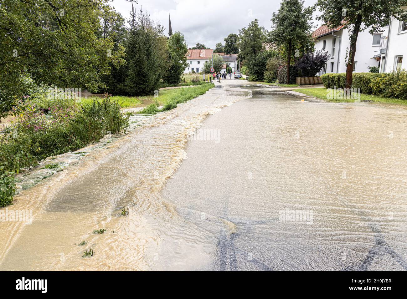 Small meadow stream floods a local road after heavy rainfall, Germany, Bavaria, Isental, Dorfen Stock Photo