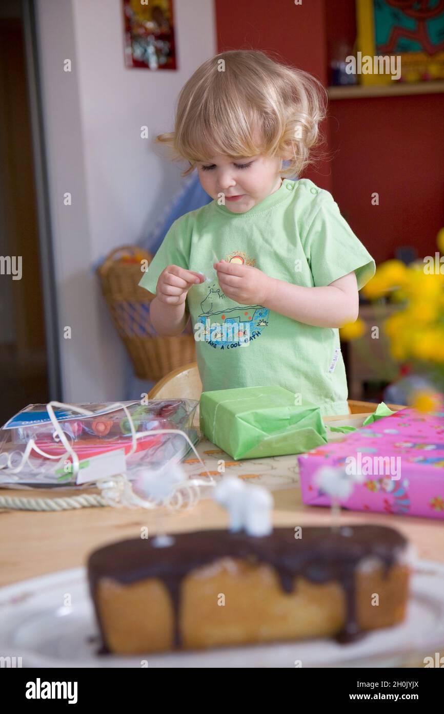 children's birthday party, little girl unwrapping her birthday presents Stock Photo