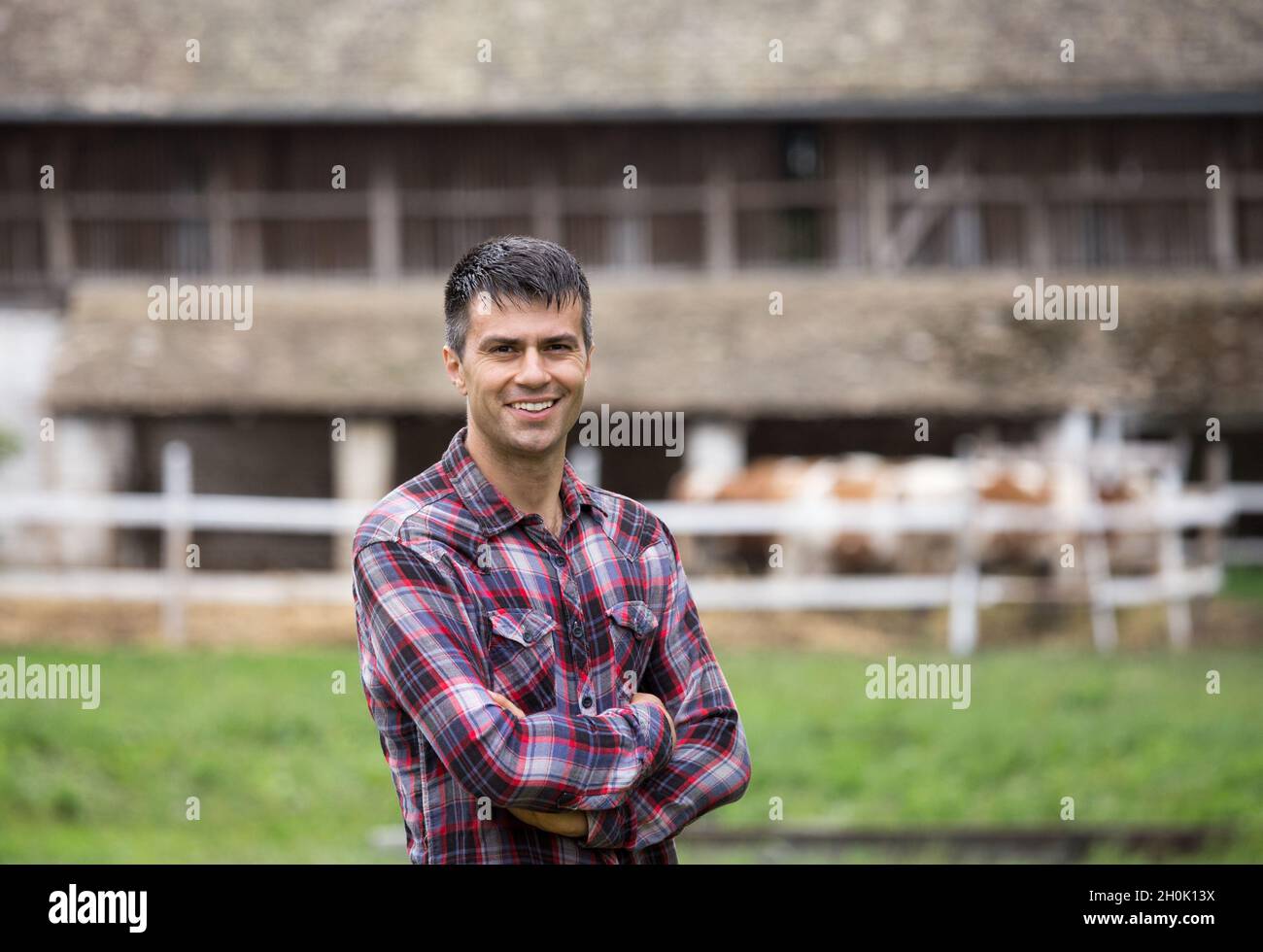 Confident handsome farmer with crossed arms standing in front of ...