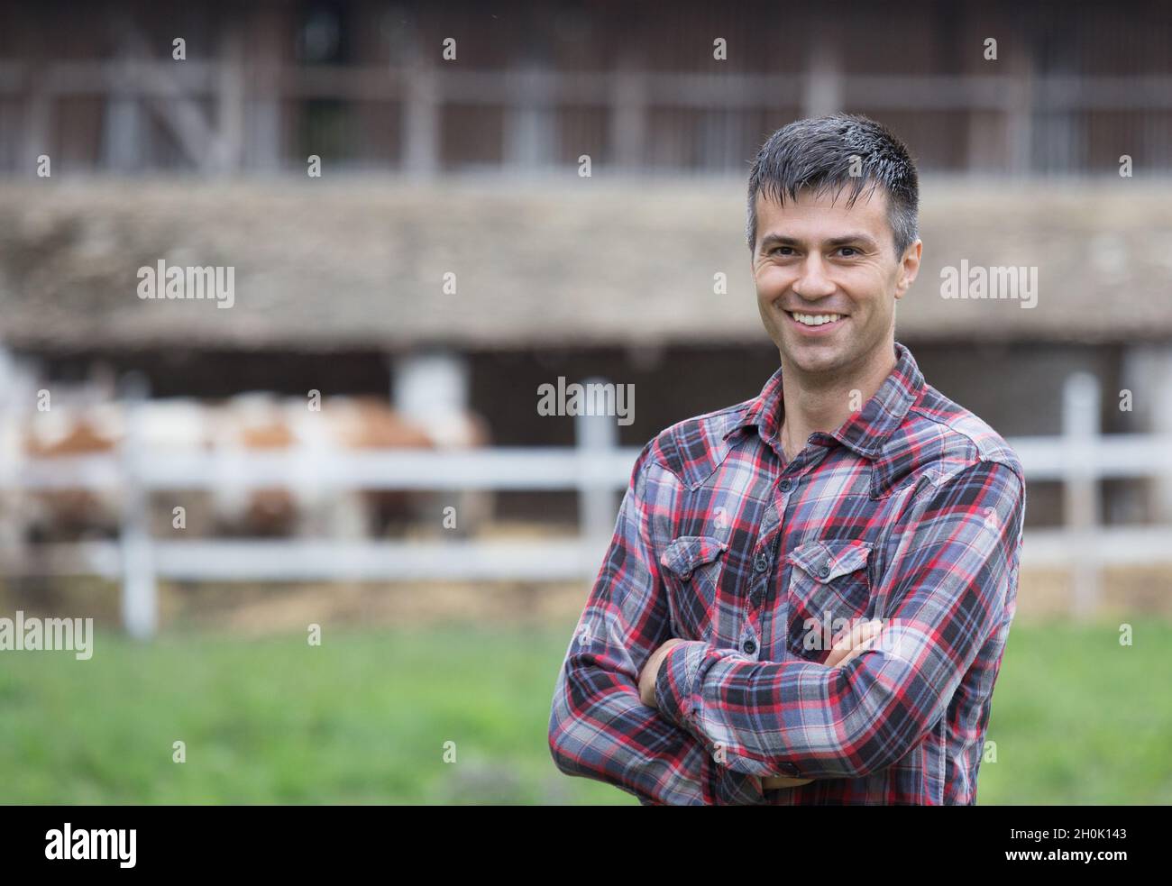 Confident handsome farmer with crossed arms standing in front of ...