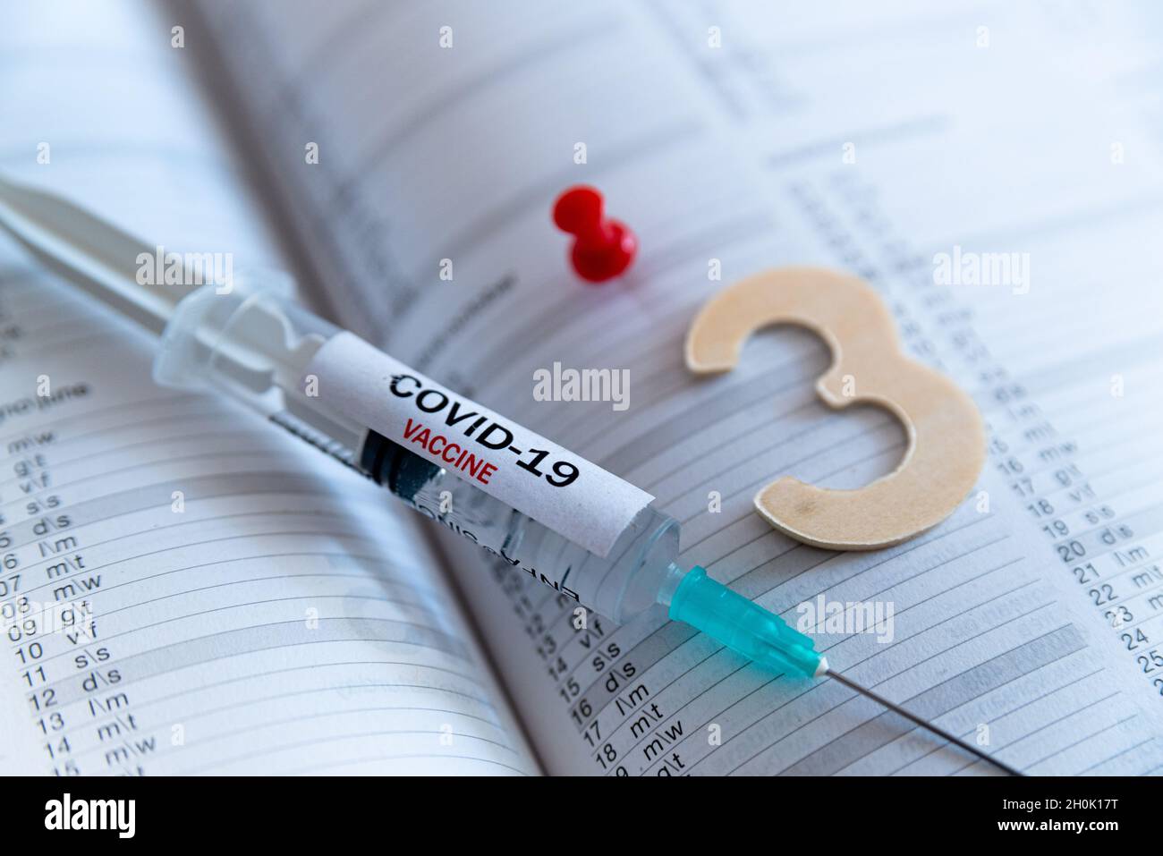 Third covid vaccine dose and jab concept. Three syringes are seen on calendar as a concept for the 3rd covid-19 vaccine dose, also called booster shot Stock Photo