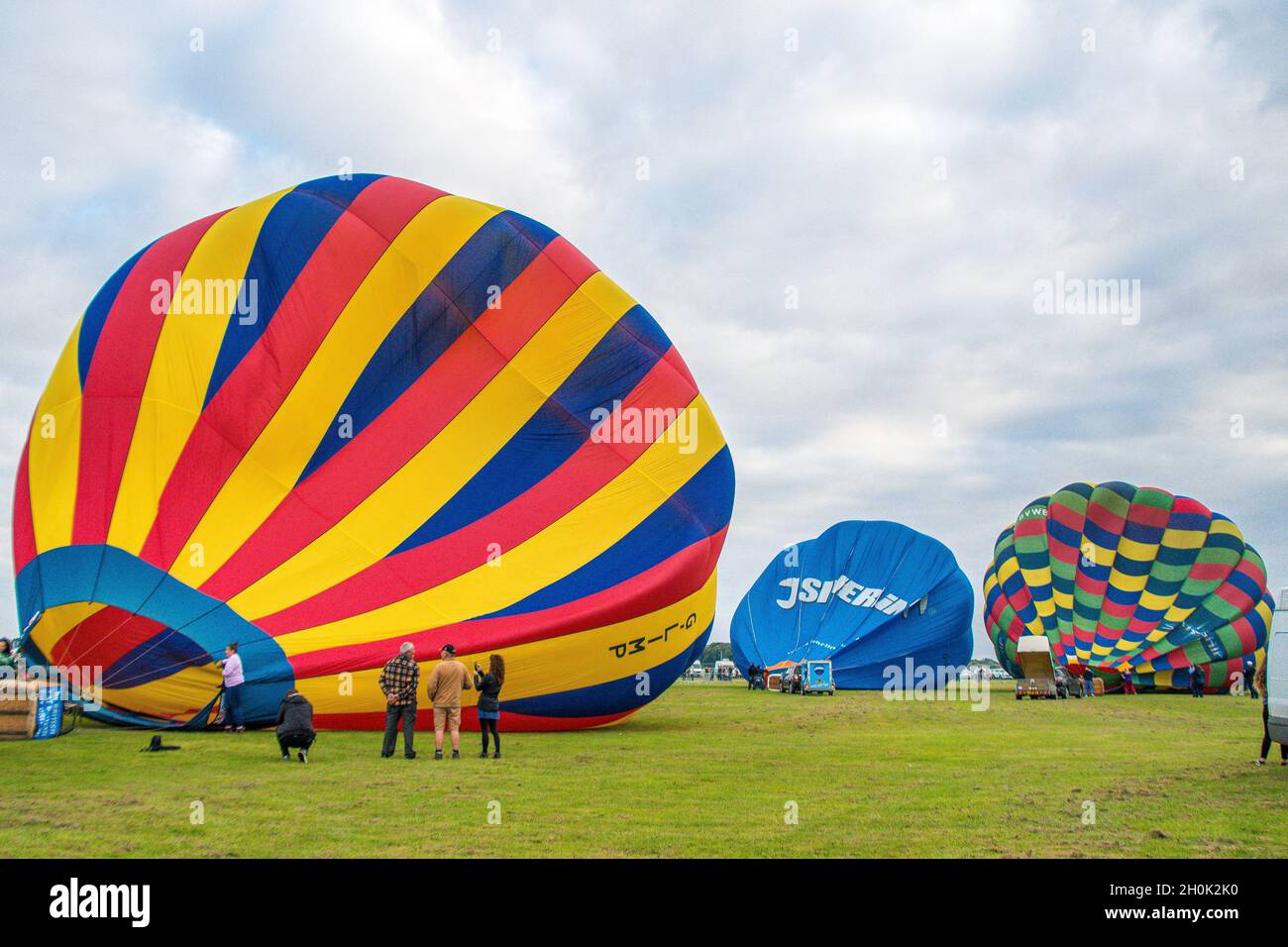 Three hot air balloons on the ground being prepared for flight with a