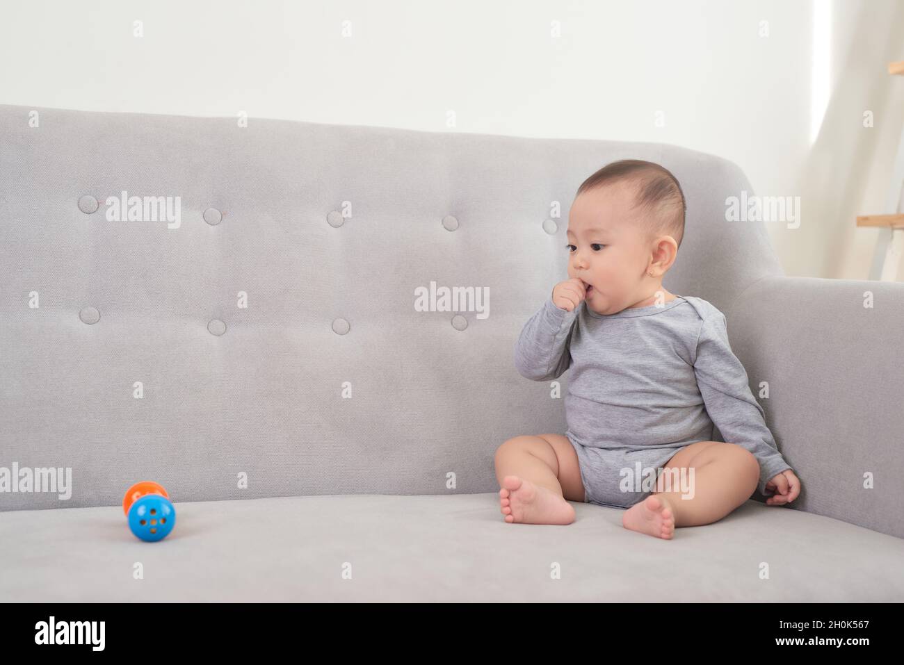pretty baby sitting and smiling on the sofa Stock Photo