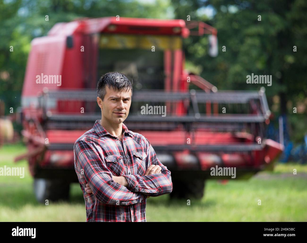 Confident handsome farmer standing with crossed arms in front of ...