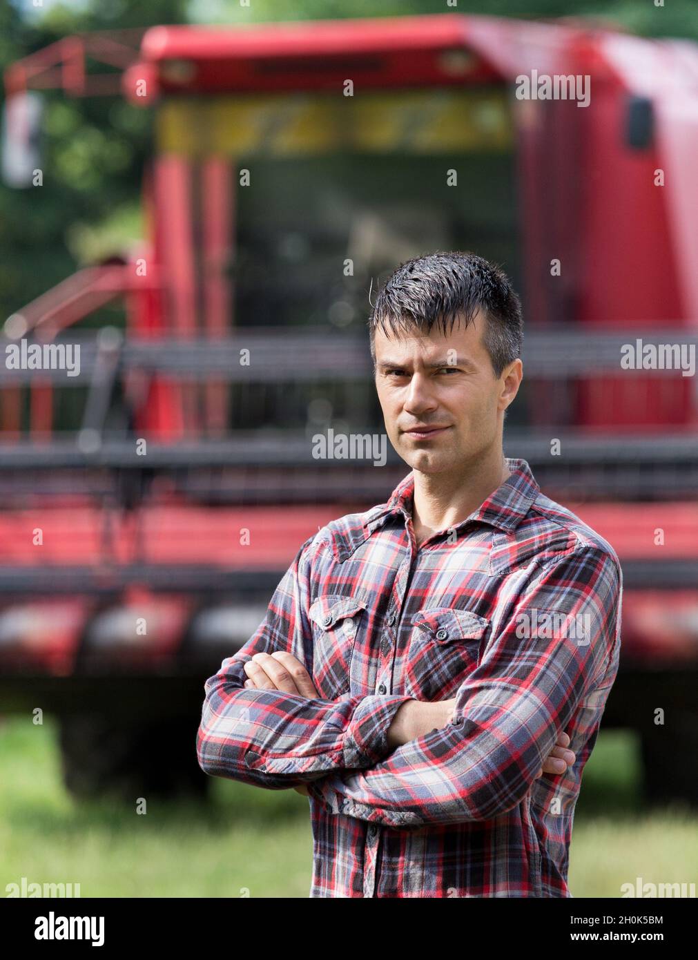 Confident handsome farmer standing with crossed arms in front of ...
