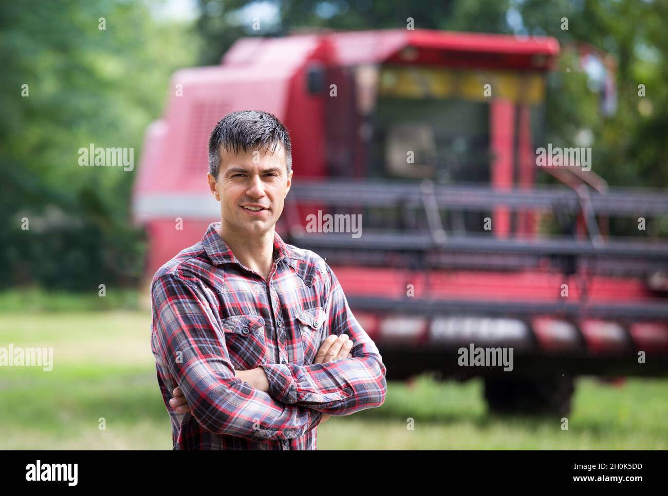 Confident handsome farmer standing with crossed arms in front of ...