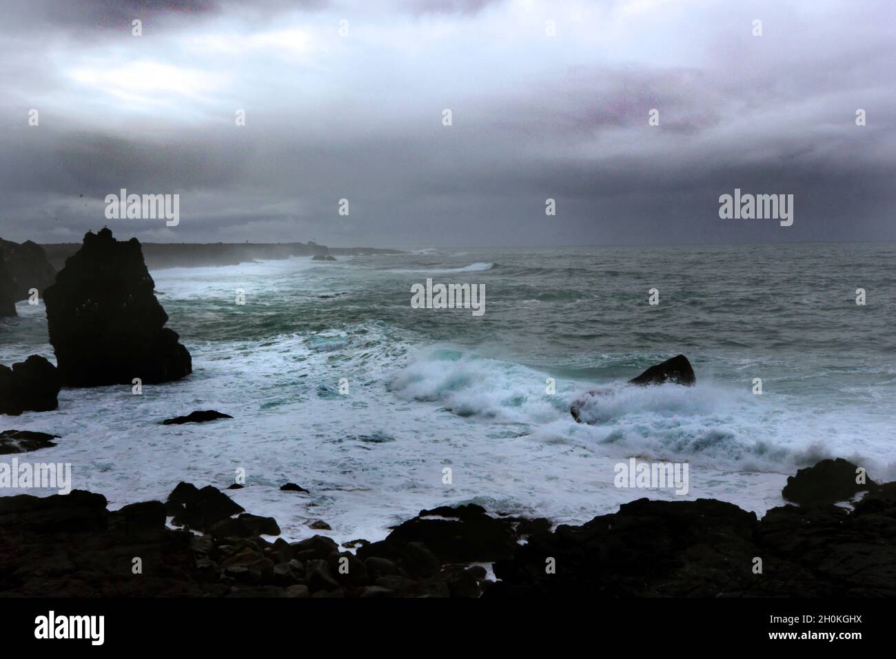 Rough seas battering the rocky shoreline and surf with stormy sky Stock Photo